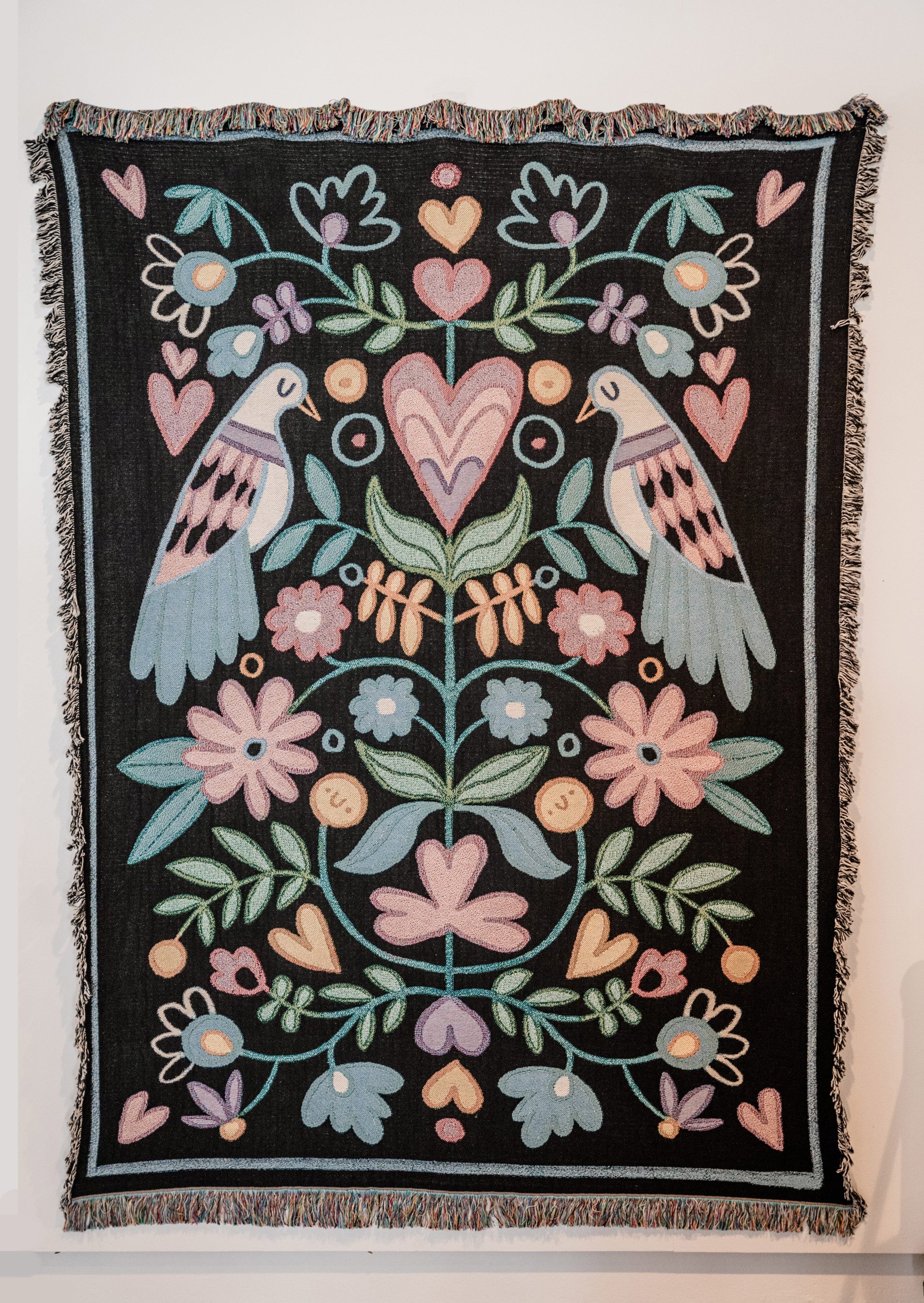 Decorative throw blanket with floral and dove bird pattern on a black background