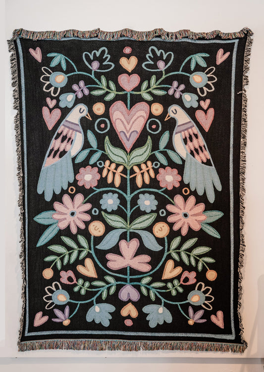Decorative throw blanket with floral and dove bird pattern on a black background